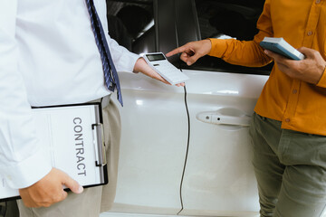 A businessman finalizes the purchase of a new car at a dealership. The salesman hands over the keys as the client signs the insurance and loan agreements, completing the secure sale and vehicle owners