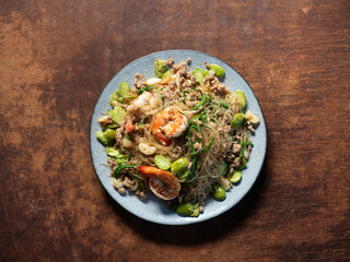 top view dish of stir fried glass noodles with shrimp, stink beans and acacia