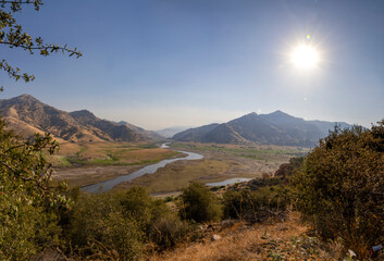 A scenic view of Lake Kaweah and the surrounding golden hills near Three Rivers, California, showcasing the dry lakebed and the winding Kaweah River under the Sierra Nevada foothills.