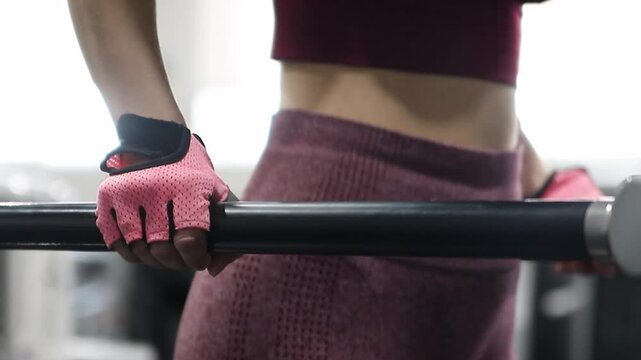 Young athletic woman doing exercise for training triceps dips on parallel bars in the gym, selective focus, camera movement.