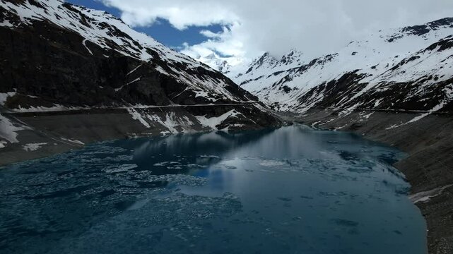 4k Drone Aerial Reverse Shot Of Vibrant Blue Glacial Water Of Lac de Moiry Dam Surrounded By Massive Snow Covered Mountains Reflecting On lake In Grimentz Switzerland