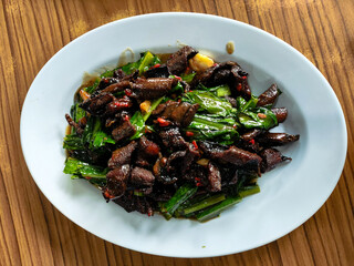 Stir-fried beef with soy sauce and greens on a plate Indonesian home-cooked meal