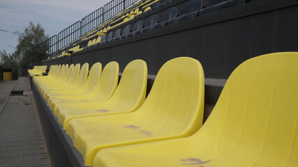 Fototapeta premium a row of yellow and black seats in the stands of an outdoor open space stadium