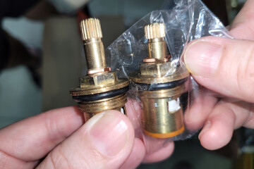 A cropped shot of adult hands holding and comparing two different sizes of valve and disc faucets