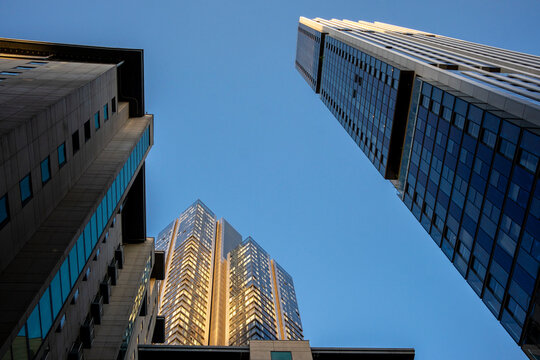 Looking up, a view captures the convergence of high-rise buildings against a crisp, blue sky, symbolizing growth, ambition, and modern architectural design in London