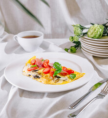 Delicious omelette with tomatoes, mushrooms, basil and ham for breakfast