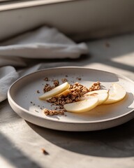 A plate with apple slices and granola, beautifully arranged in natural light.
