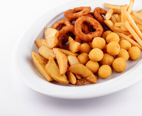 Big plate of french fries, potato wedges, onion rings and croquettes on white background