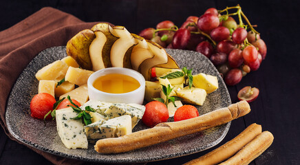 Gourmet cheese plate offering variety of textures and flavors with honey and grapes