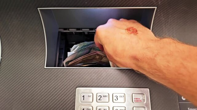 A man's hand puts Russian banknotes into the ATM bill acceptor. simplicity and convenience of replenishing a bank account.