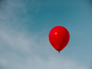 Obraz premium A single red balloon floats in a clear blue sky