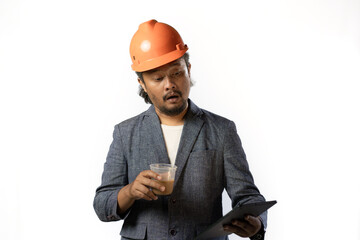 Indonesian male construction worker standing confidently and optimistically carrying a tablet and a cup of coffee, industrial and construction concept, isolated white background.

