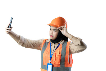 young Asian female construction worker wearing hijab and safety gear taking selfie, industrial and construction concept, isolated white background.