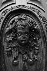 This is a striking black and white photograph that captures a detailed carving of a childs face, highlighting the artistry involved