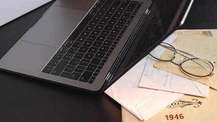 Minimalist workspace with laptop, vintage letters, and glasses blending modern work life with...