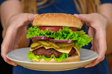 Dziewczyna je dużego cheeseburgera, apetyczny fast food z bliska © Paweł Kacperek