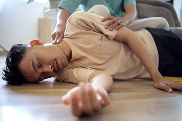 Man Doing CPR First Aid, Checking Pulse to Asian Guy at Home First Aid Emergency Rescue Concept
