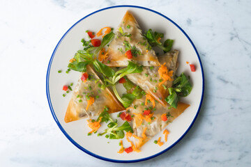 Baked brick pastry triangles filled with eggplant. Top view table with  decoration.