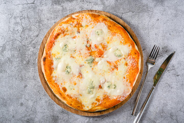 Four cheese neapolitan pizza on wooden cutting board on stone table