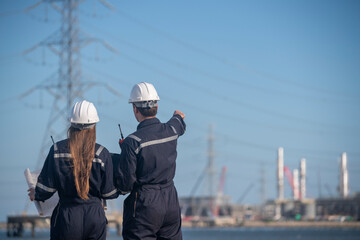 Engineers wearing safety gear, including hard hats examining survey blueprint , tablet industrial...