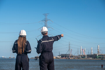 Engineers wearing safety gear, including hard hats examining survey blueprint , tablet industrial...