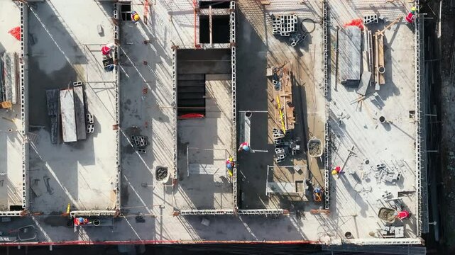 An aerial shot of a highrise construction site shows workers at work, scattered materials, and equipment, highlighting modern architectures essence in urban development