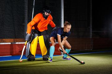 Female field hockey player attacking the goalie to score a goal