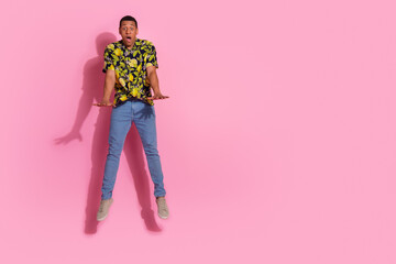 Full length photo of young guy amazed jumping pushing invisible things dressed tropical print...