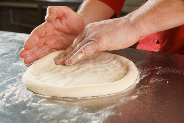 Shaping pizza dough in the kitchen