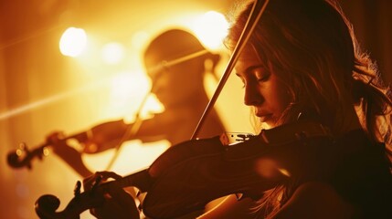 Fototapeta premium Beautiful musicians playing violins in warm stage lights create a magical atmosphere for the audience.