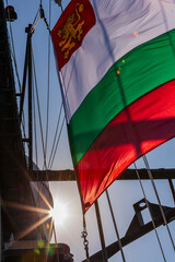 Bulgarian flag on a warship. Bulgarian flag white green and red on the background of a beautiful sky and sun rays.