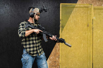 A guy in civilian clothes practices tactical shooting with night vision and a ak rifle with a...