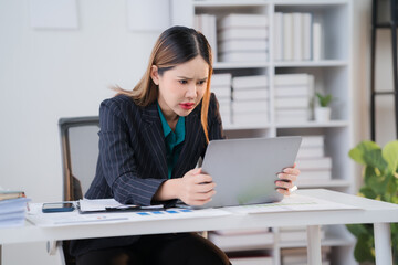 Overwhelmed and Stressed: A young Asian businesswoman grapples with a challenging workload, her...