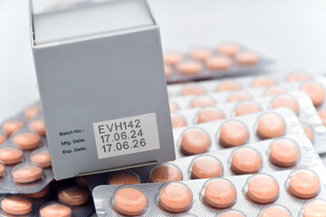 Manufacturing date and expiry date on some pharmaceutical packaging with strips of orange tablets.