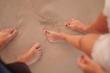 Two pairs of feet on the sand, he and she. Feet of a man and a woman in the sea on the sand.