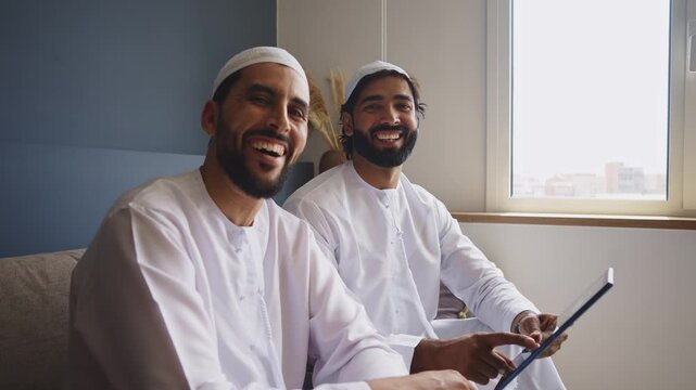 Cinematic video of two friends spending time together in a modern apartment in the united arab emirates. Emirates people with the traditional white kandura in Dubai.