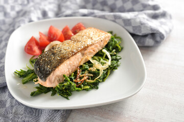 Salmon fillet roasted with skin on a bed of spinach vegetables and tomatoes, healthy meal to lose weight with low carb diet, copy space