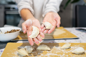 A woman holds ready-made homemade dumplings, varenyky in her hands. Ukraine cuisine, natural homemade food