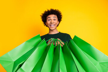 Photo of nice young man hold shop bags wear pullover isolated on yellow color background