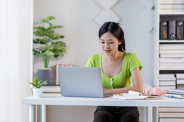 Portrait of a modern business asian woman, woman in a green shirt working on a laptop in the home office
