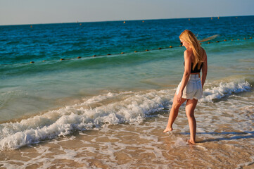 Woman having fun at the beach. A beautiful girl with long white hair plays mountain with the waves. Rest, travelling.