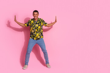 Full length photo of handsome young guy push side wall empty space dressed stylish tropical print garment isolated on pink color background