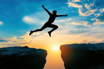 Silhouette of a person jumping between cliffs against a glowing sunset sky