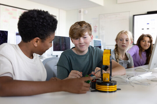 School boy students working on a robotic arm in class
