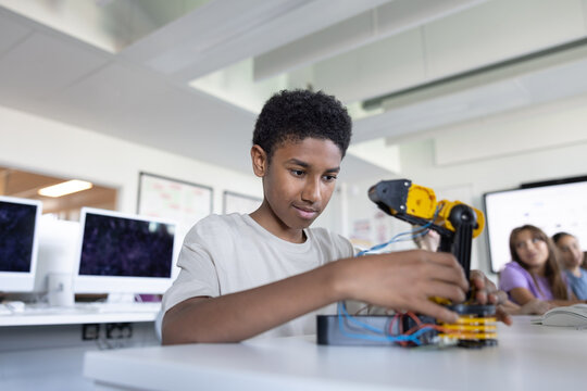 African American school boy working on a robotic arm in class