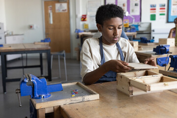 African American boy learning carpentry in woodworking class at school