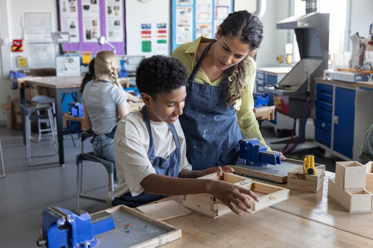 Boy student showing teacher his project in woodworking class - Powered by Adobe
