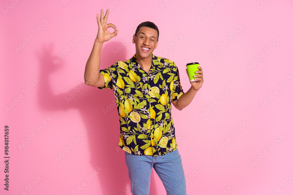 Poster Photo portrait of handsome young guy hold coffee paper cup okey dressed stylish tropical print garment isolated on pink color background