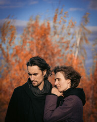Fototapeta premium a couple of a guy and a girl of European appearance are hugging in the fall, the blue sky hangs, the clouds are gloomy, the wind is blowing