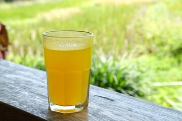  refreshing glass of warm orange juice on a wooden table with a natural background. Ideal for use...